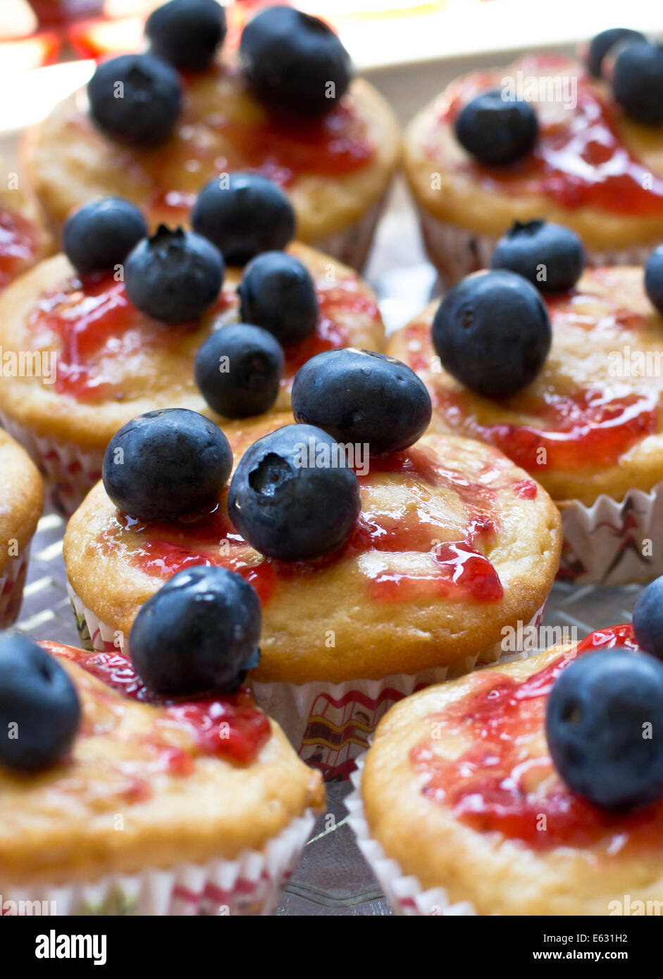 Closeup of low fat vanilla cupcakes with strawberry jam and fresh blueberries for a topping. Stock Photo