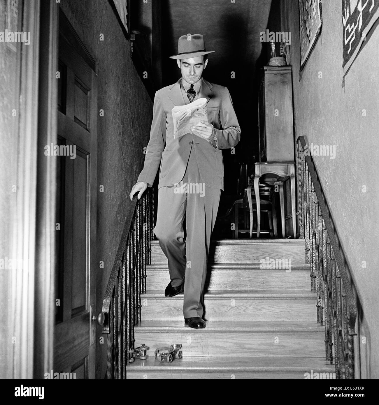1930s 1940s ACCIDENT ABOUT TO HAPPEN MAN WALKING DOWN STAIRS SLIP ON PAIR OF ROLLER SKATES Stock Photo
