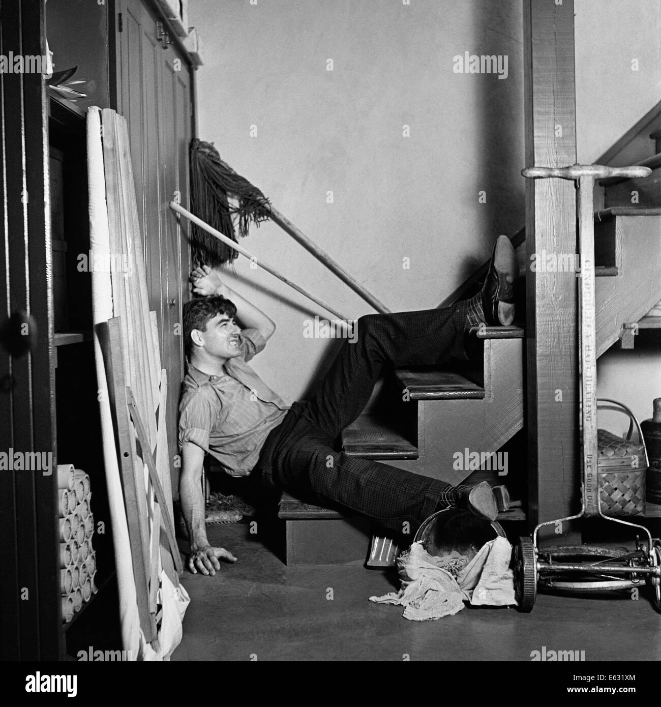 1930s 1940s MAN LYING AT BOTTOM BASEMENT STAIRS FALLEN HOUSEHOLD ACCIDENT INJURY Stock Photo