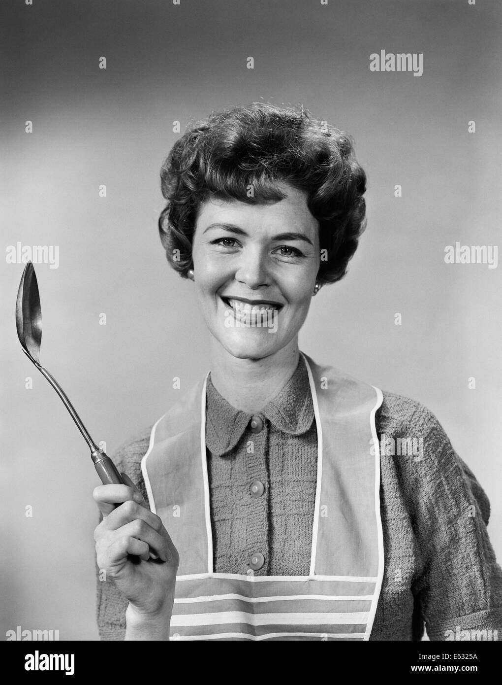 1950s 1960s PORTRAIT SMILING WOMAN HOUSEWIFE WEARING APRON HOLDING