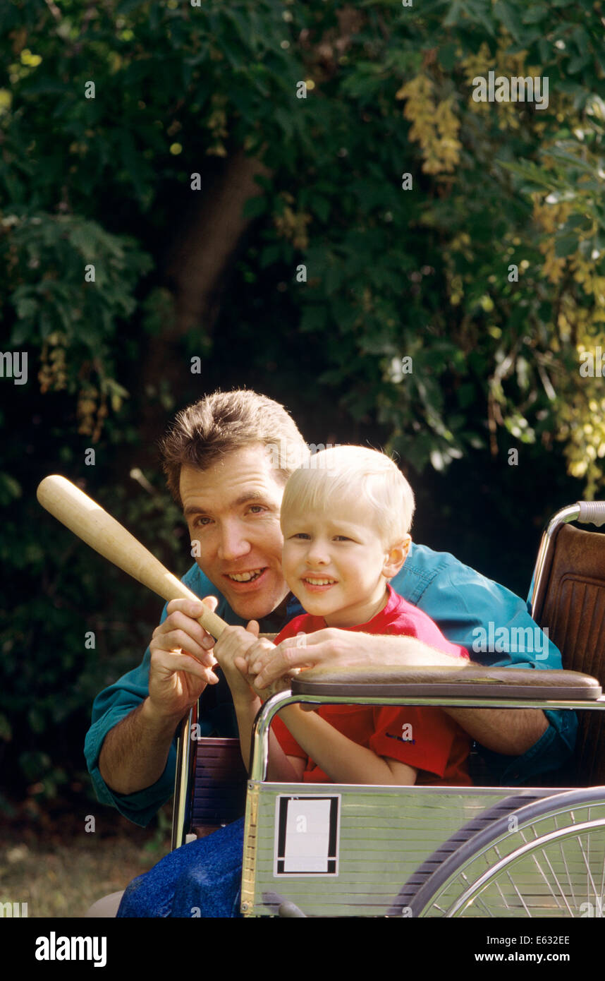 FATHER TEACHING SON TO PLAY BASEBALL SON IN WHEELCHAIR Stock Photo