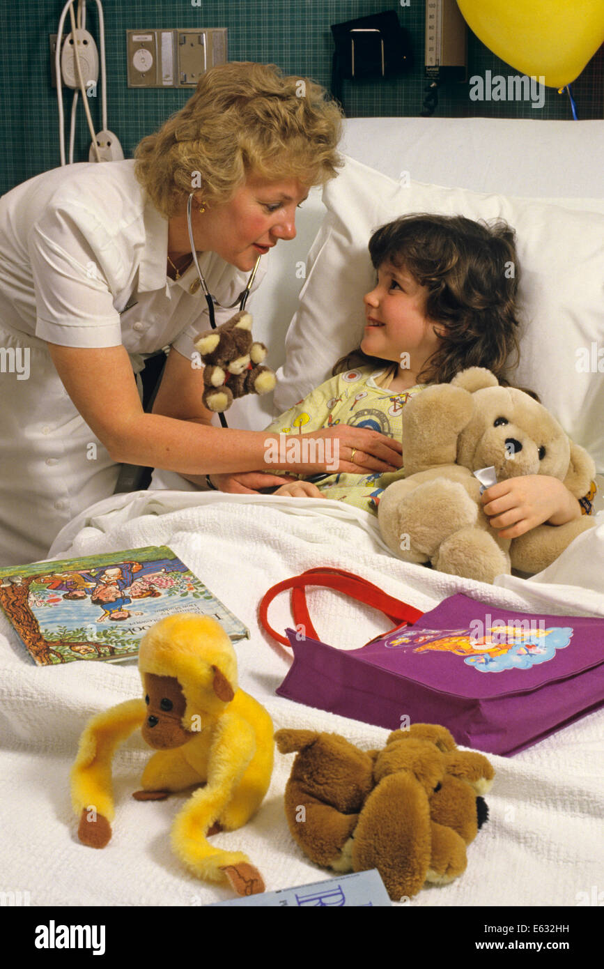 1980s NURSE WITH YOUNG PATIENT IN HOSPITAL BED Stock Photo