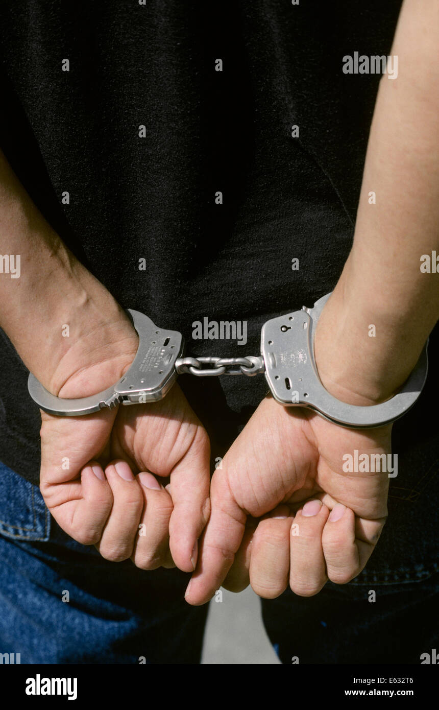 1990s CLOSE-UP OF ANONYMOUS MALE HANDS IN HANDCUFFS Stock Photo