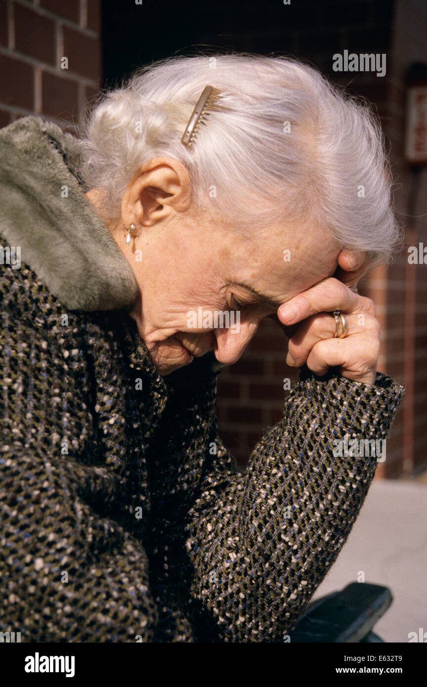 1980s OLDER WOMAN HOLDING HEAD IN HAND Stock Photo