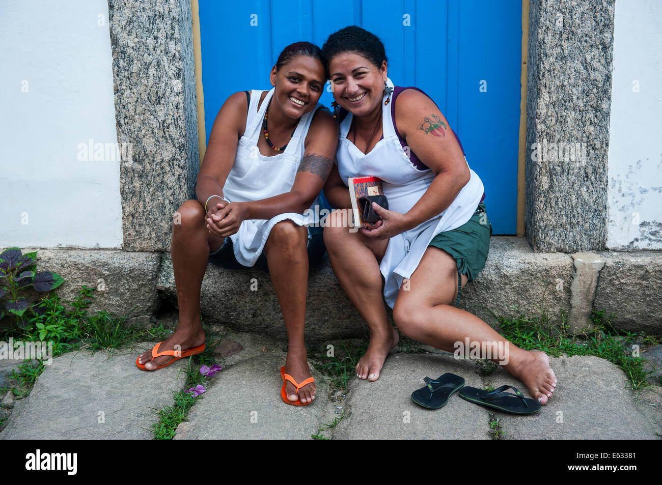 Two friendly women sitting on the doorstep, Paraty, Rio de Janeiro State, Brazil Stock Photo