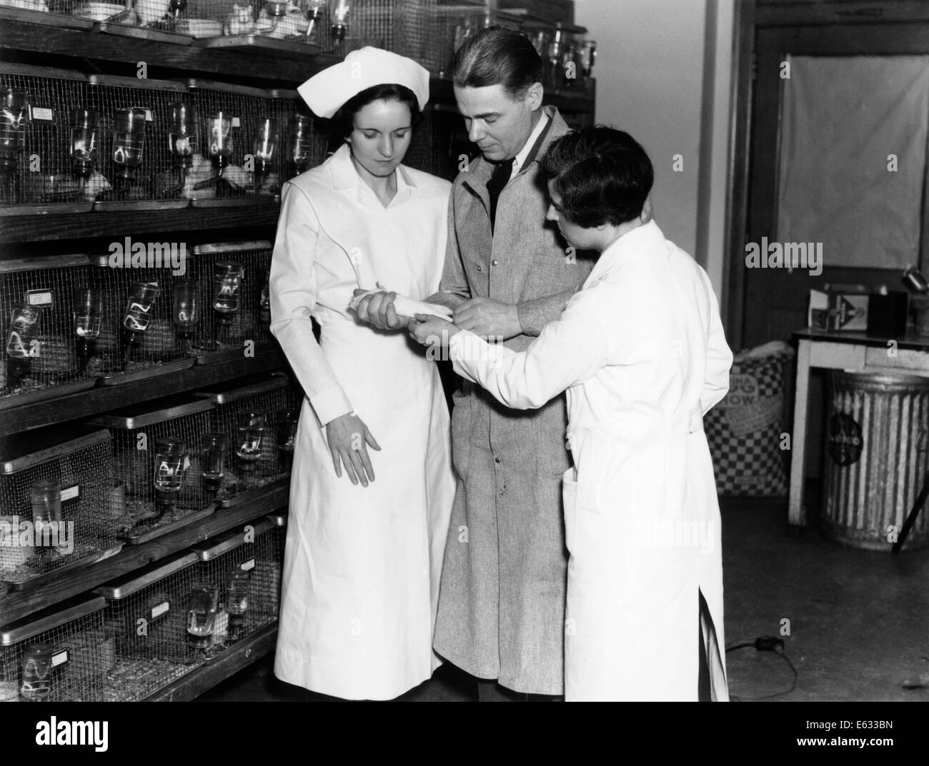1930s TWO NURSES AND LAB TECHNICIAN MAN WOMEN IN HOSPITAL LABORATORY REVIEWING NOTES Stock Photo