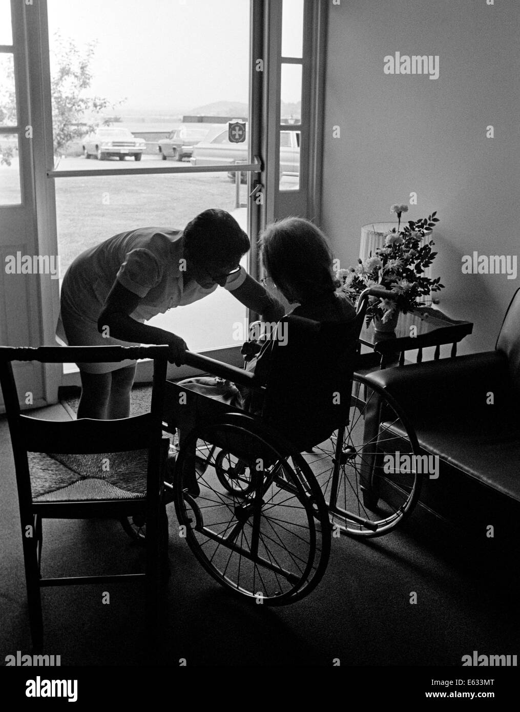 1970s ANONYMOUS SILHOUETTED NURSE HELPING ELDERLY PERSON SITTING IN WHEELCHAIR ALL IN SILHOUETTE Stock Photo