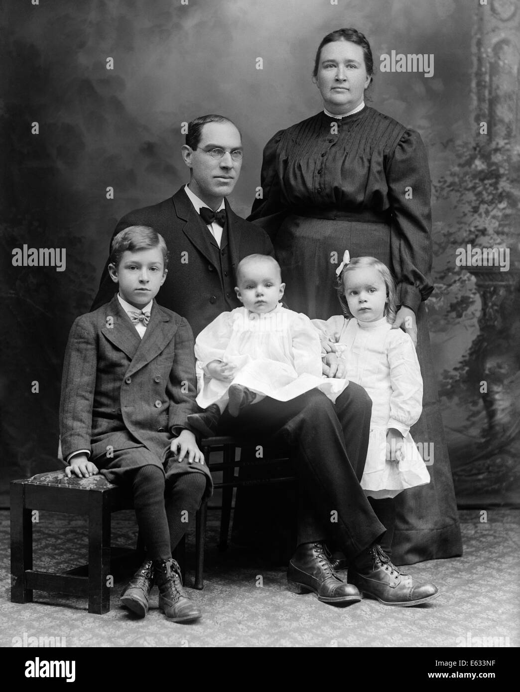 1890s FORMAL STUDIO PORTRAIT OF FAMILY MOTHER FATHER THREE CHILDREN SON DAUGHTER BABY Stock Photo