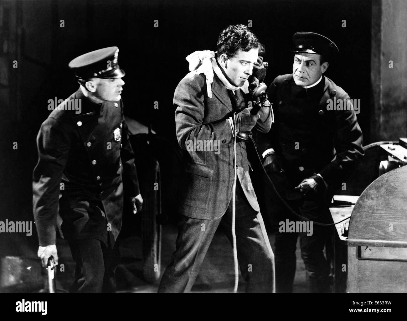 1930s TWO ARMED POLICE LOOKING AT ANXIOUS DESPERATE MAN ROBBERY VICTIM TALKING ON TELEPHONE Stock Photo