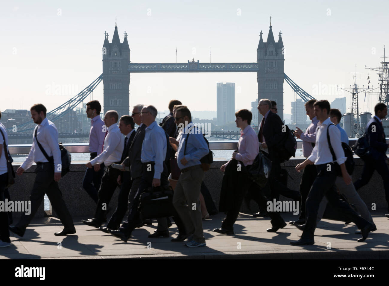 Morning commuters crossing London Bridge with Tower Bridge behind, London, England, United Kingdom, Europe Stock Photo