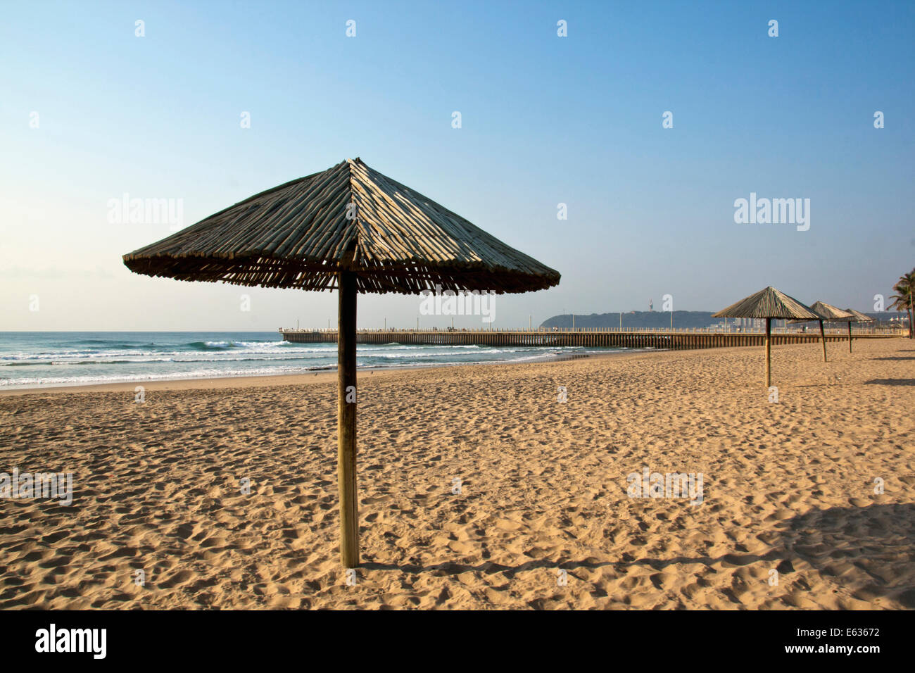 Early morning, sun shade umbrellas lined up on empty beach in Durban