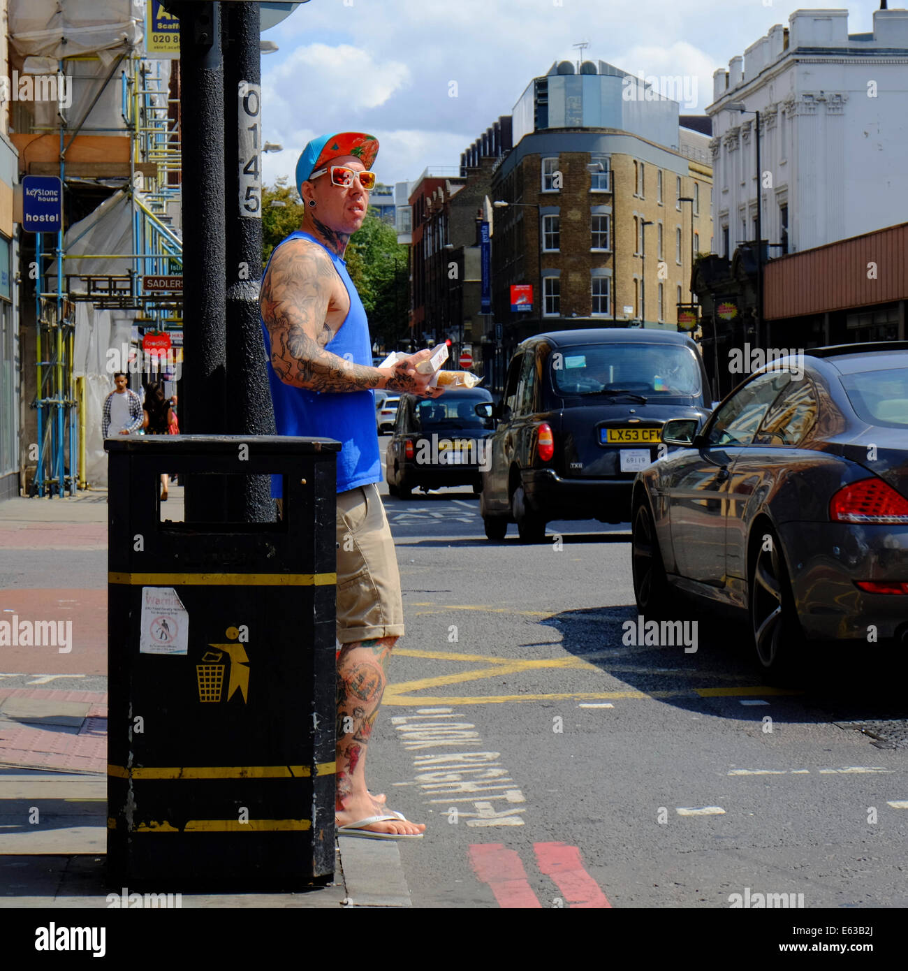 Man with Tattoos waiting to cross a road Stock Photo