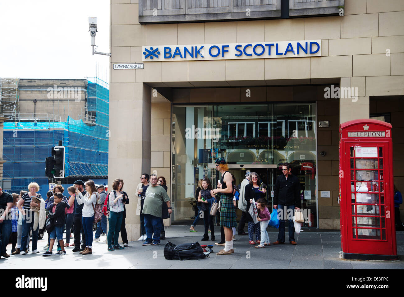 Scotland 2014. Edinburgh  Festival. Street entertainer wearing a kilt outside the Royal Bank of Scotland, the Lawnmarket Stock Photo