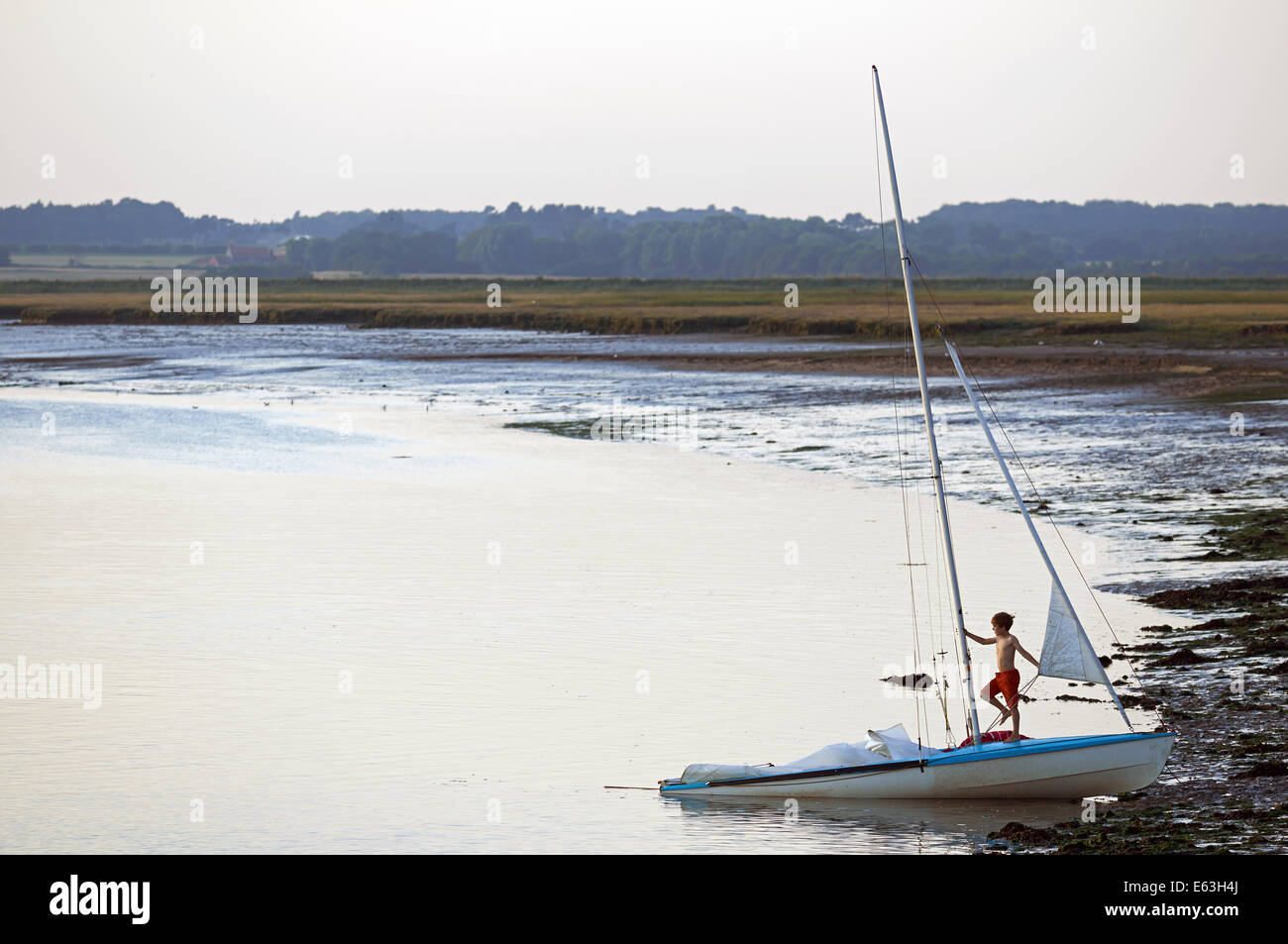 Boy playing on a sailing boat, Bawdsey Ferry, Suffolk, UK. Stock Photo