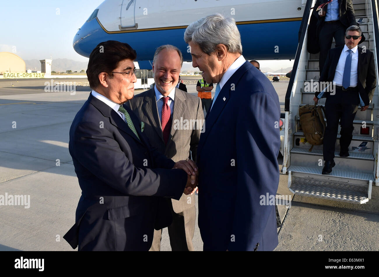 U.S. Secretary of State John Kerry, flanked by U.S. Ambassador to Afghanistan James Cunningham, shakes hands with Afghan Ministry of Foreign Affairs Chief of Protocol Hamid Siddiq upon arriving in Kabul on August 7, 2014, for discussions about the country Stock Photo