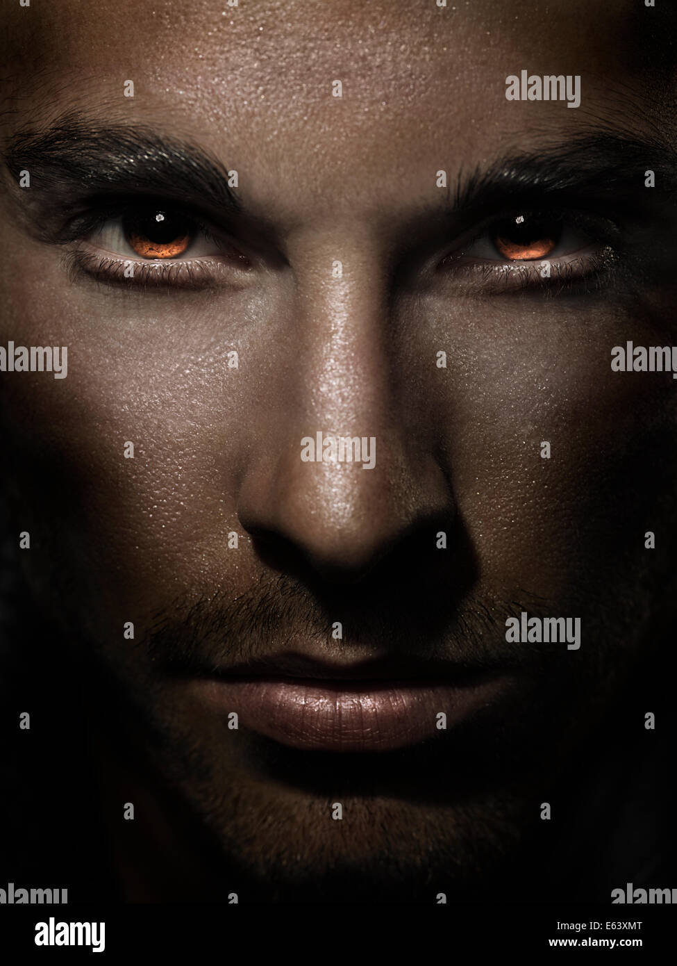 Dramatic closeup of man face with fierce eyes burning with red Stock