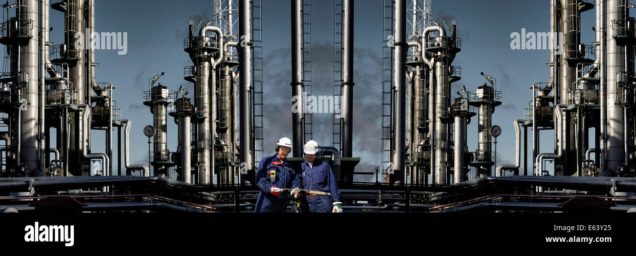 two oil-workers standing in front of large refinery industry Stock Photo