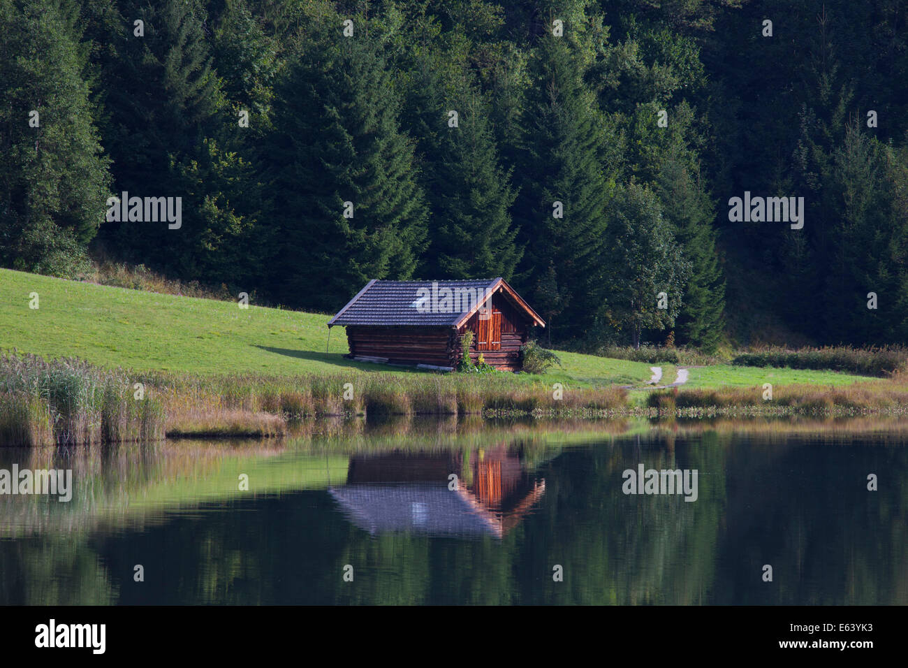 Hayrack mirrored in the calm water of the lake Geroldsee. Karwendel Mountains, Bavaria, Germany Stock Photo