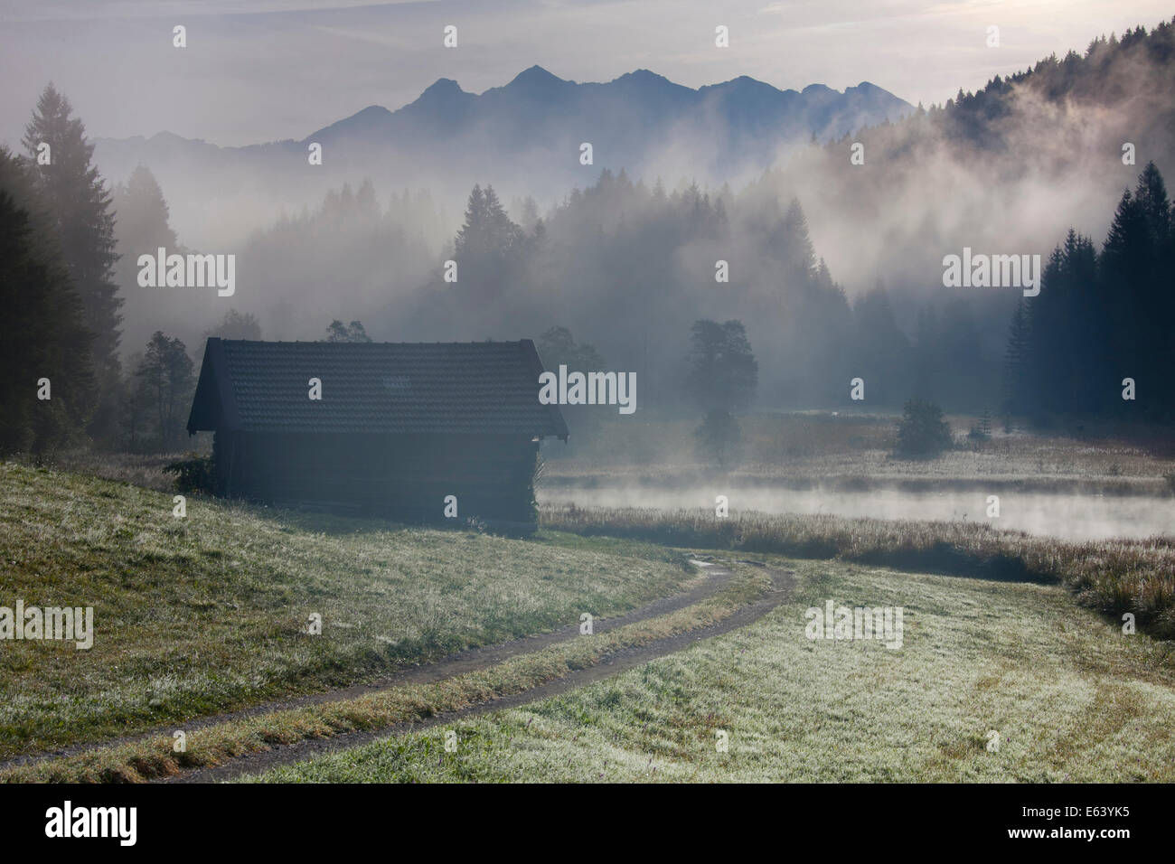 Hayrack at the lake Geroldsee in morning mist. Karwendel Mountains, Bavaria, Germany Stock Photo