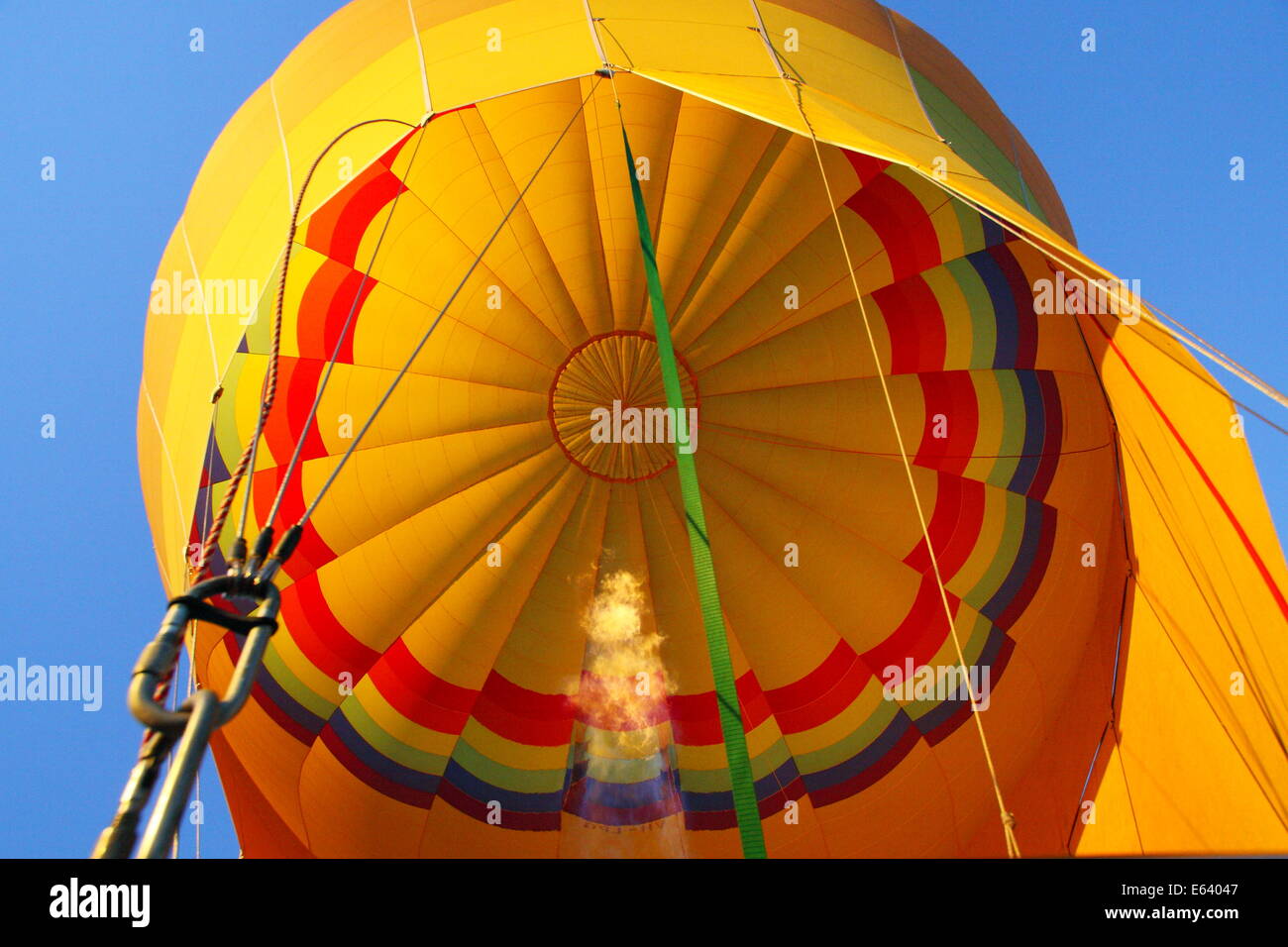 A rainbow colored hot air balloon inflating in front of a clear blue ...
