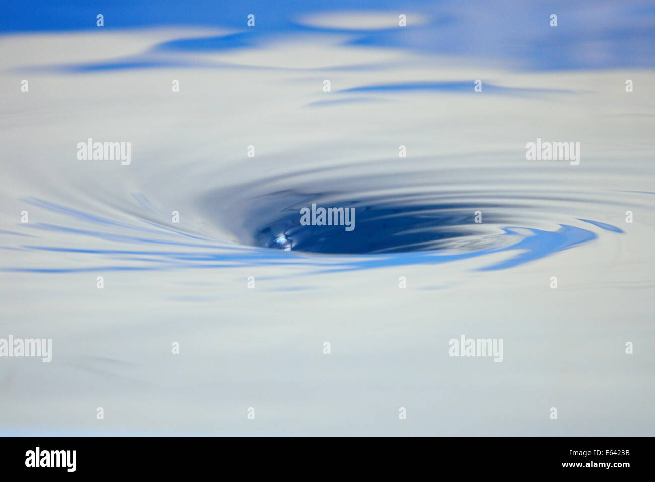 Water swirls and bubbles as it descends into a whirlpool. Stock Photo