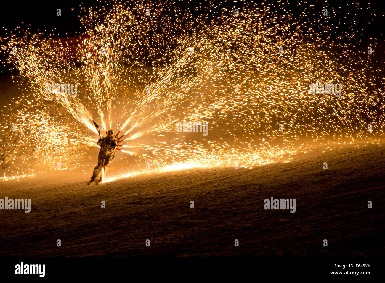 Skier coming down a ski slope with fireworks attached to his back in a performance to celebrate the New Year Stock Photo