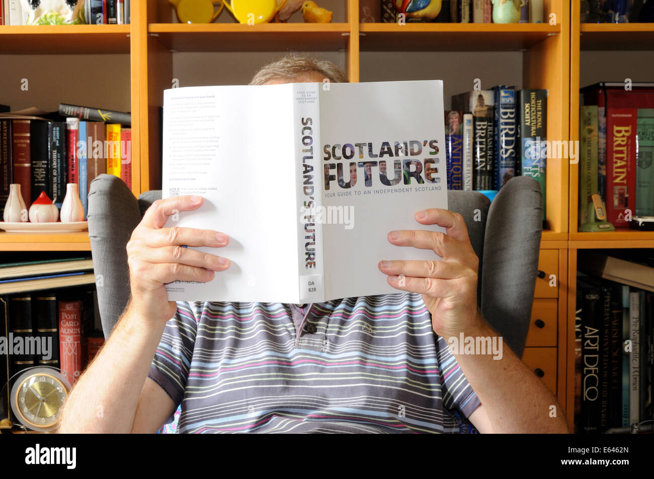 Man in his fifties reading 'Scotland's Future' at home Stock Photo