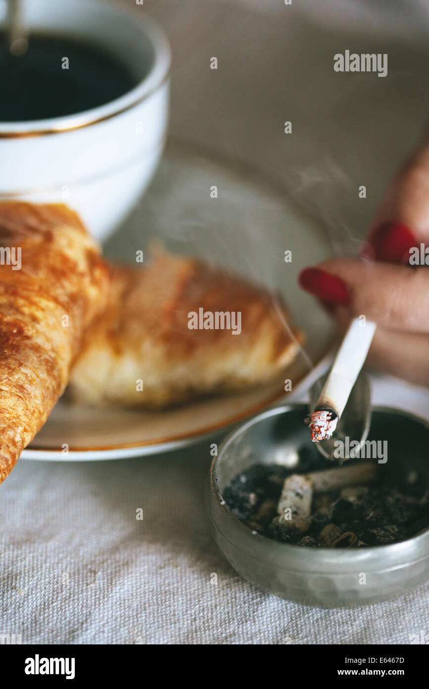 Woman smoking at breakfast Stock Photo