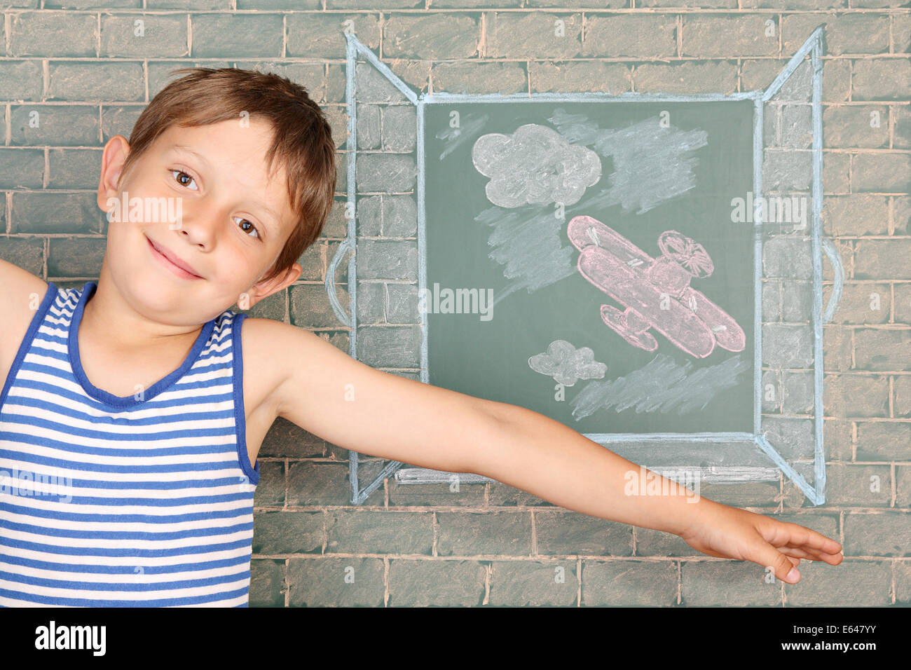 Flight of fantasy, schoolboy before chalkboard with drawing of airplane back of open window Stock Photo