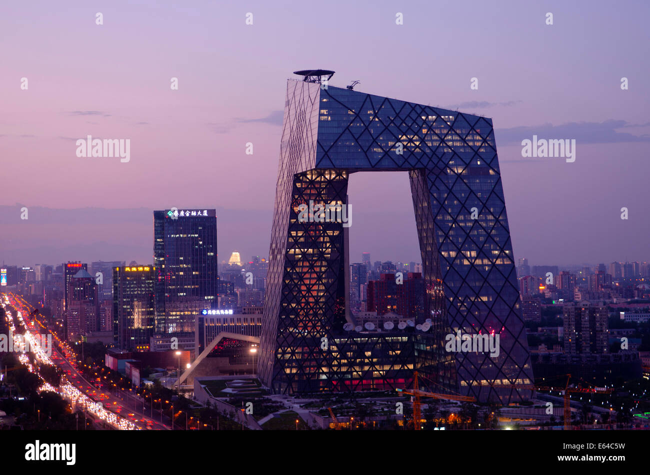 Beautiful view of the skyline of the Chinese capital city and the famous landmark of the CCTV headquarter, with the lights of the traffic on the third ring road and offices and buildings illuminating the scene in the early evening. Rare panoramic scene during blue hour just after sunset with clear skies in Guomao, the Central Business District if Beijing, located in the Chaoyang district, China, PRC. © Olli Geibel Stock Photo