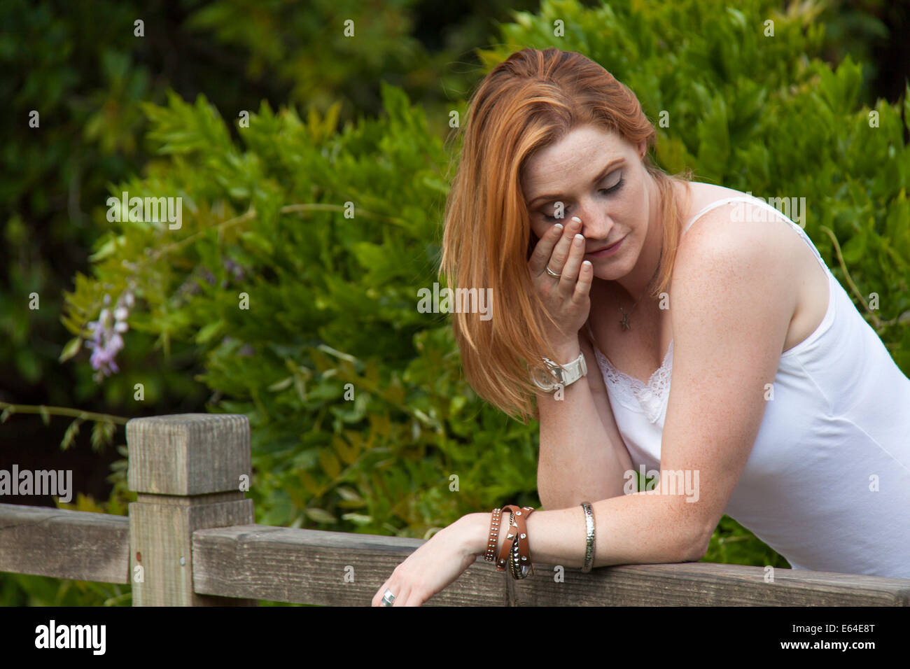 A red haired young girl crying by a bridge Stock Photo