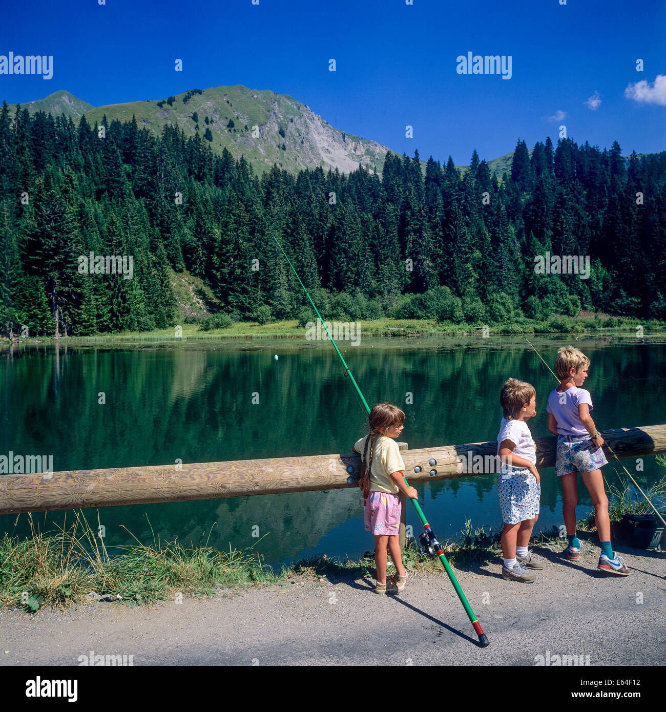 Children angling at Les Mines d'Or lake Morzine resort Savoy French Alps France Stock Photo