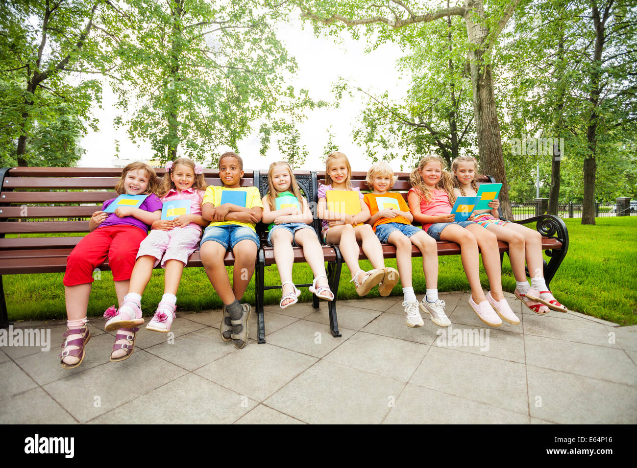 Children sitting in a row on bench with notebooks Stock Photo - Alamy