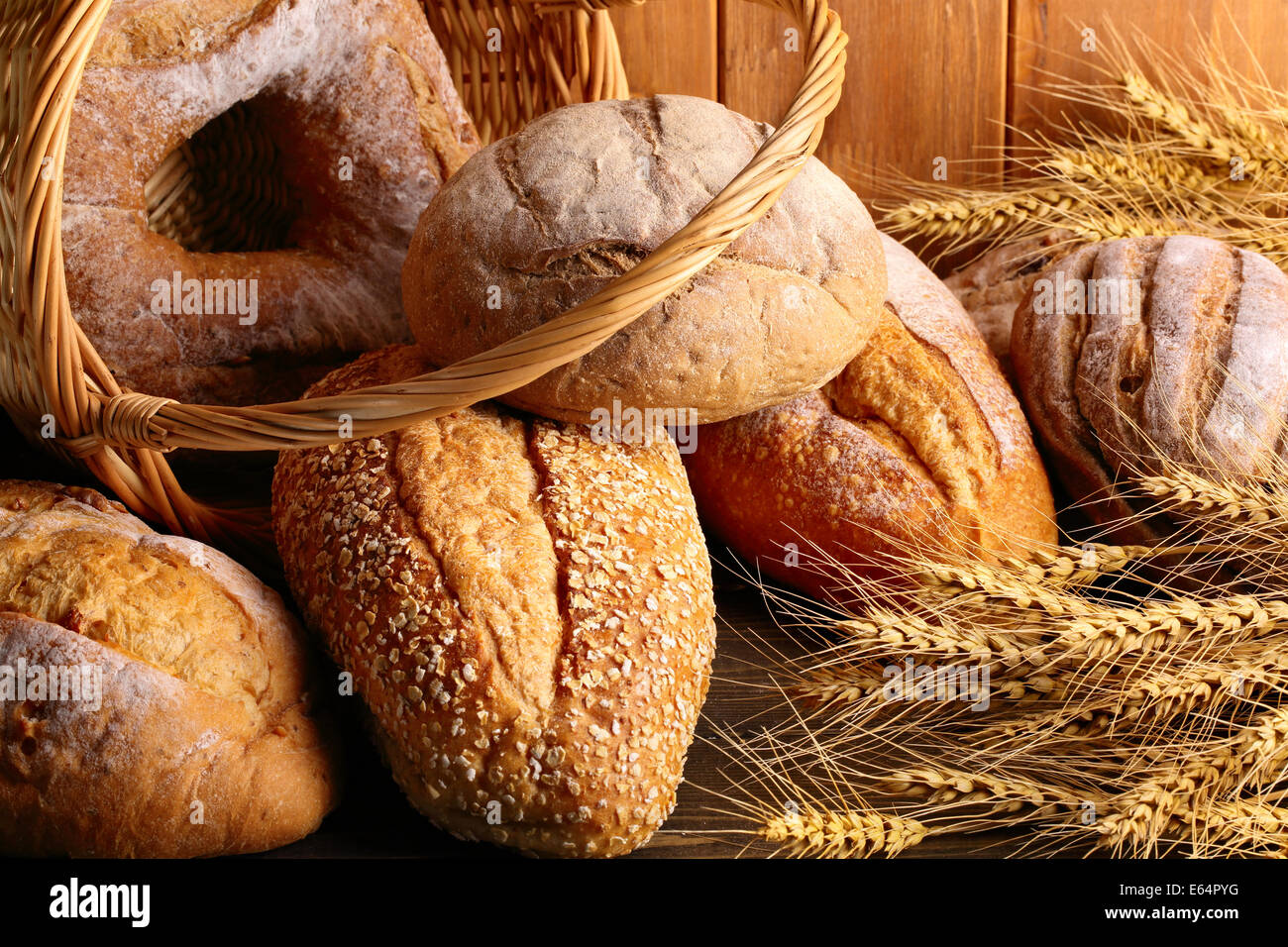 Whole grain wheat bread in basket with wheat ears. Stock Photo