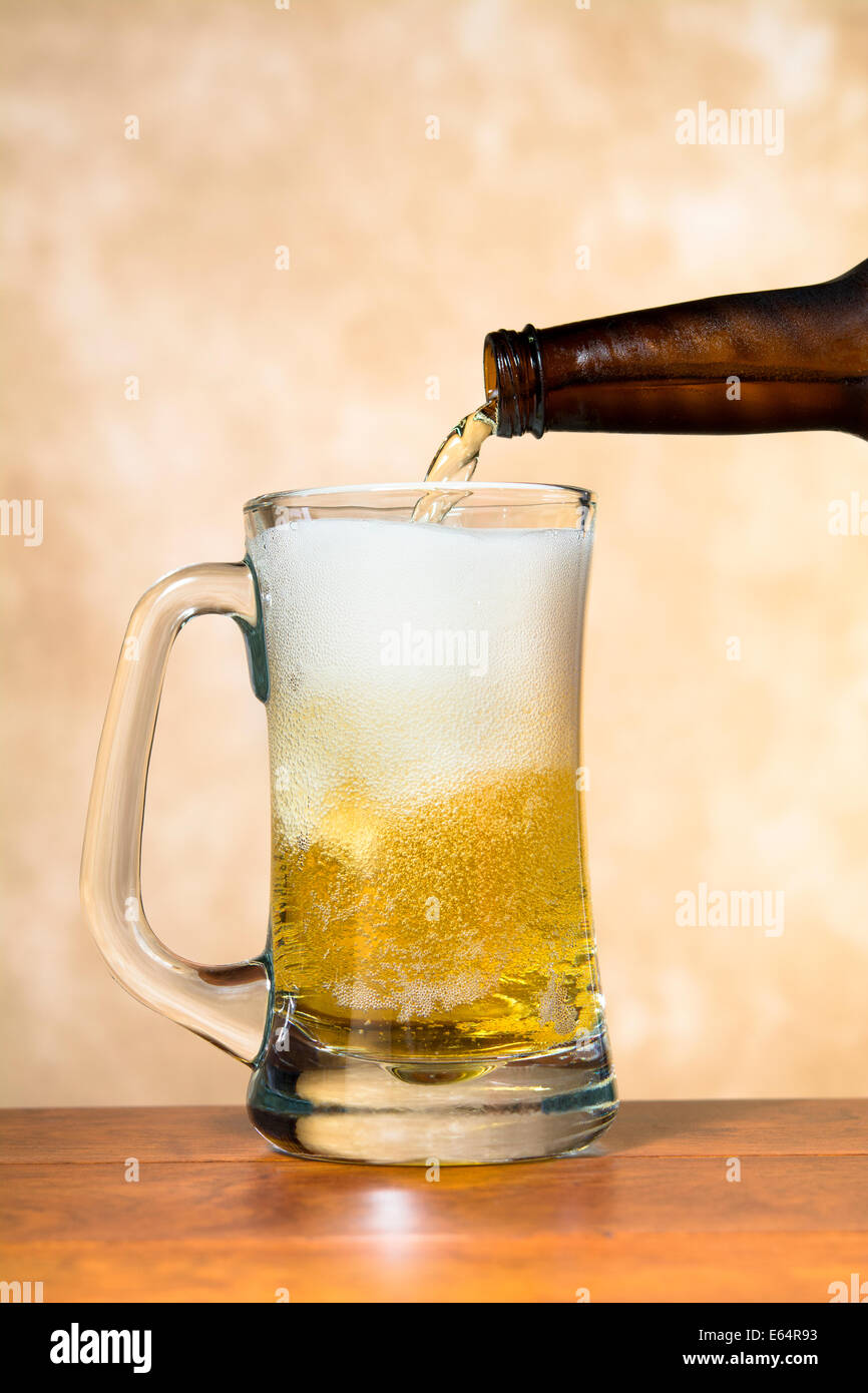 Ice cold, refreshing beer being poured into a classic pint beer mug