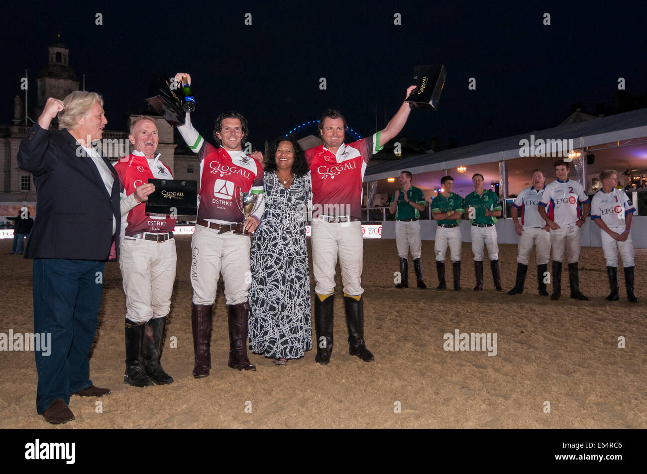 London, UK, 14 August 2014.  The famous Horse Guards Parade hosts City Polo, an inaugural evening of international arena polo.  Pictured : Team Wales receive their winner's trophy from designer, David Emanuel.   Credit:  Stephen Chung/Alamy Live News Stock Photo