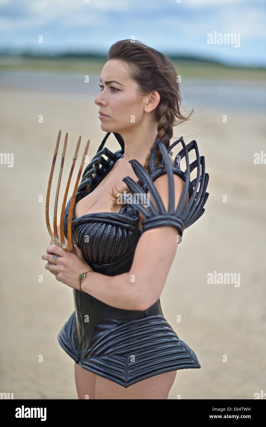 Woman dressed up with a futuristic space look costume holding a rusty trident, creating a modern interpretation of Salacia, Nept Stock Photo