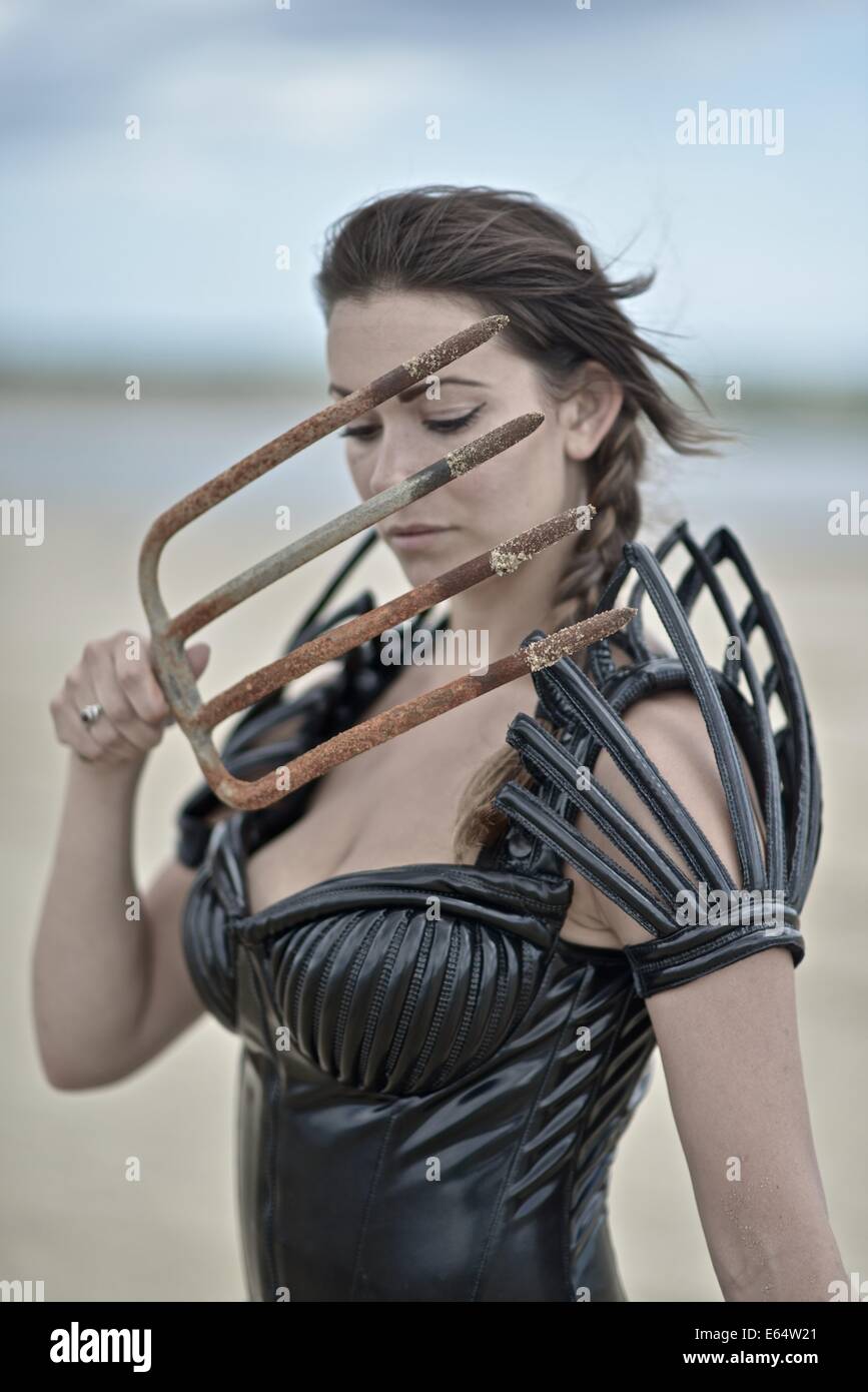 Woman dressed up with a futuristic space look costume holding a rusty trident, creating a modern interpretation of Salacia, Nept Stock Photo