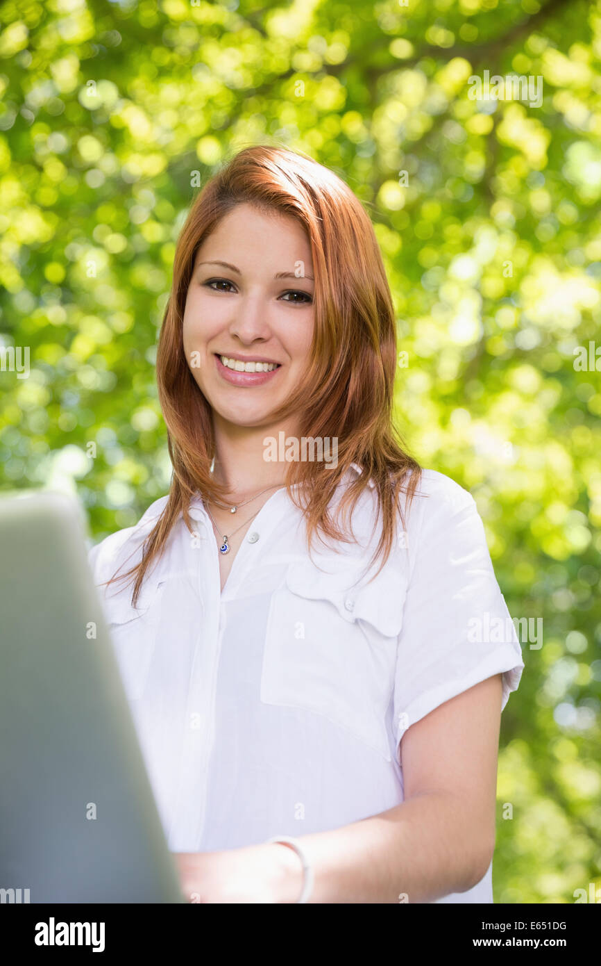 Pretty redhead using her laptop in the park Stock Photo - Alamy