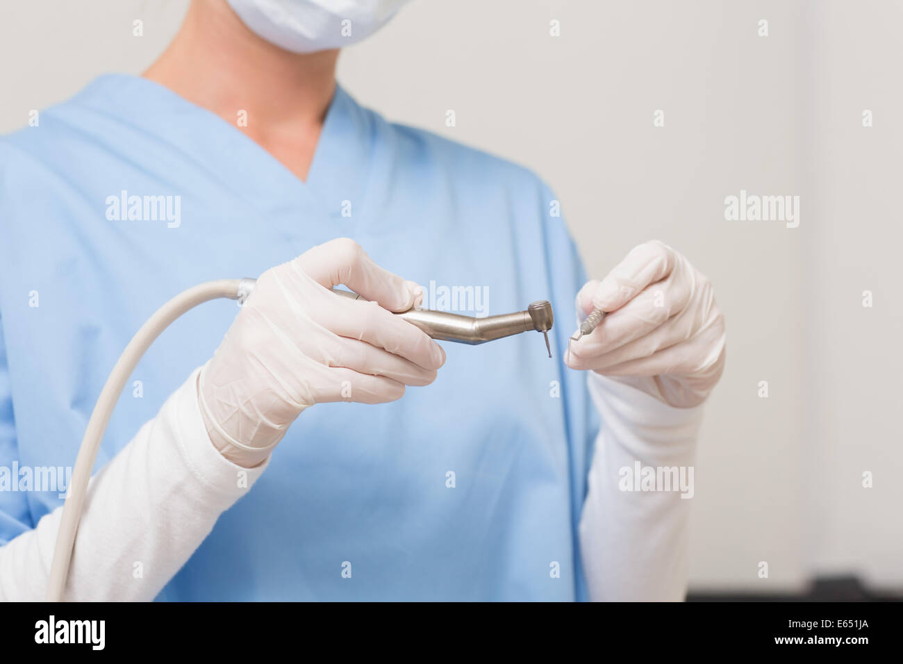 Dentist in blue scrubs holding drill Stock Photo Alamy