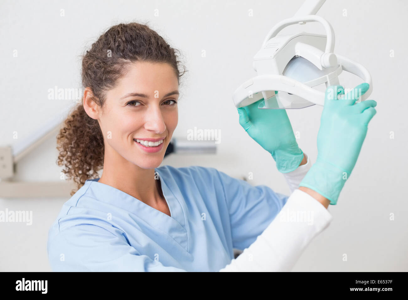 Dentist in blue scrubs smiling at camera beside light Stock Photo Alamy