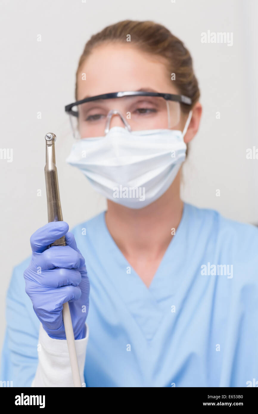 Dentist in blue scrubs holding dental drill Stock Photo Alamy
