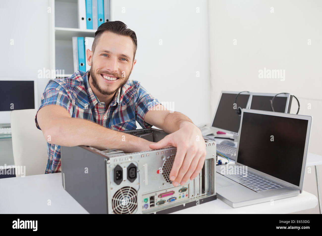 Computer engineer smiling at camera beside open console Stock Photo - Alamy