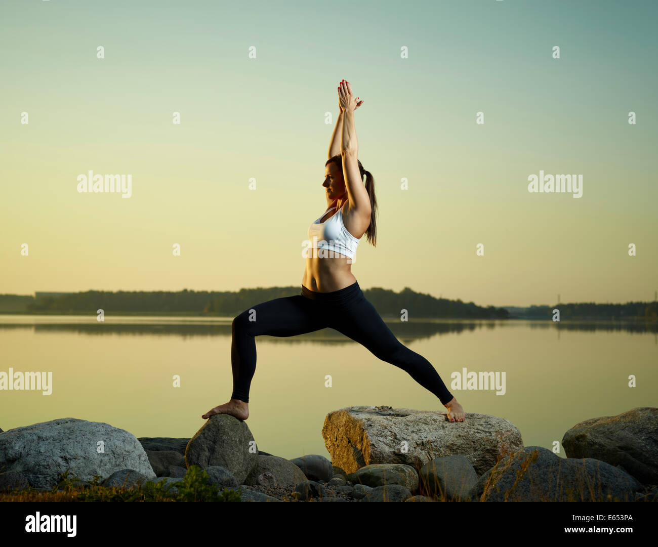 The beautiful young woman exercise yoga early at morning, calm sea on background Stock Photo