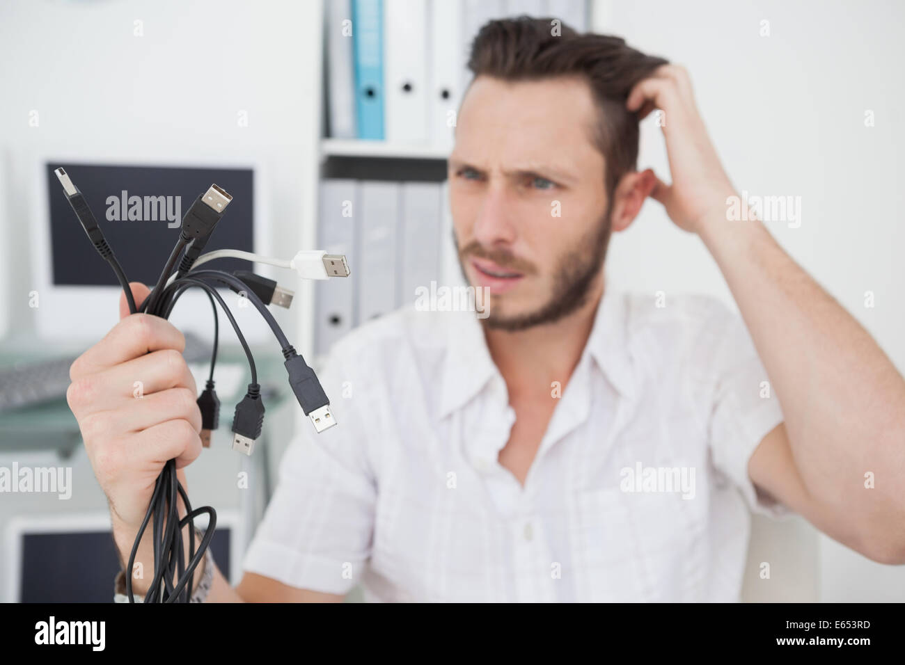 Confused computer engineer looking at wires Stock Photo - Alamy