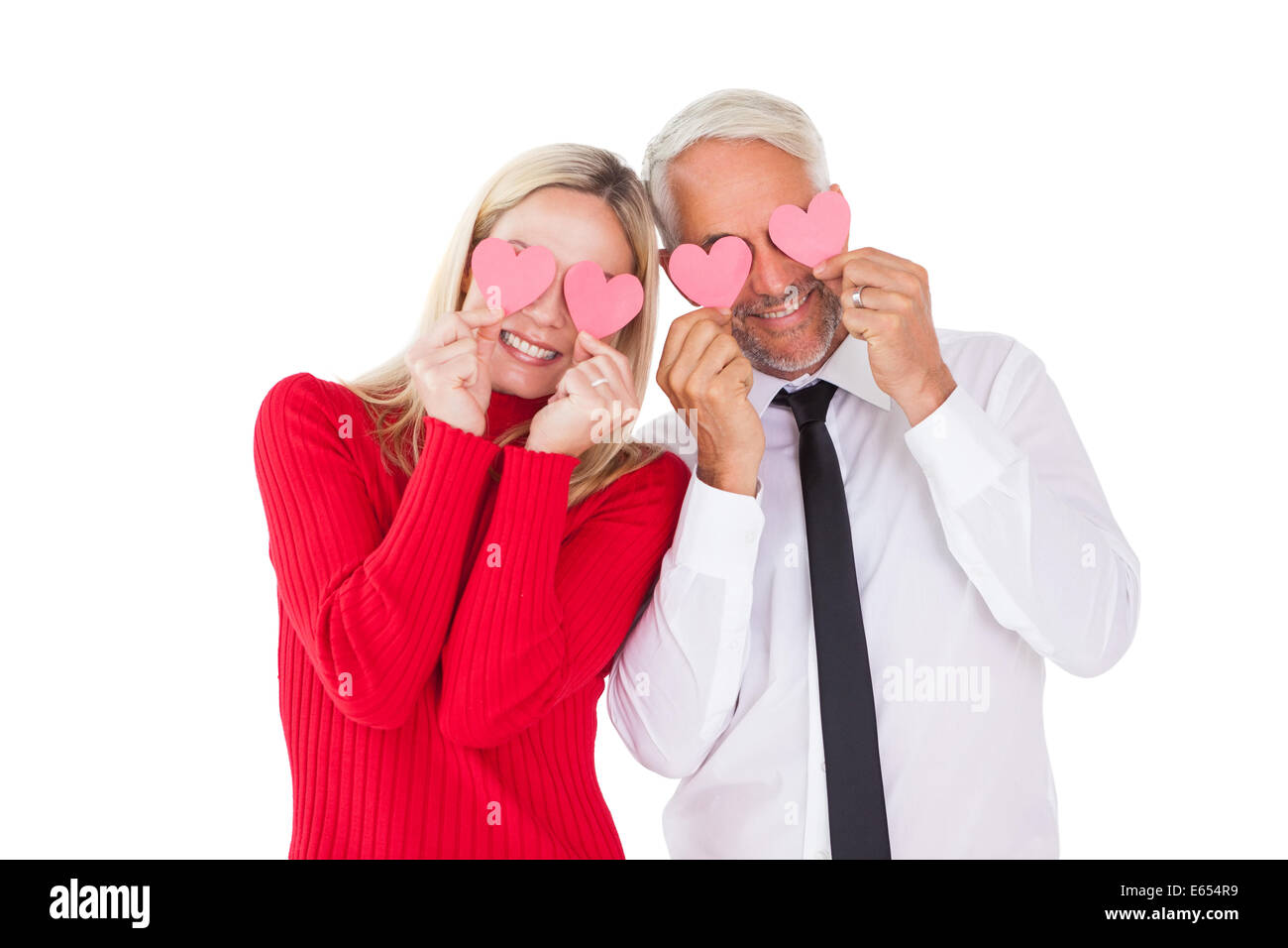 Silly couple holding hearts over their eyes Stock Photo