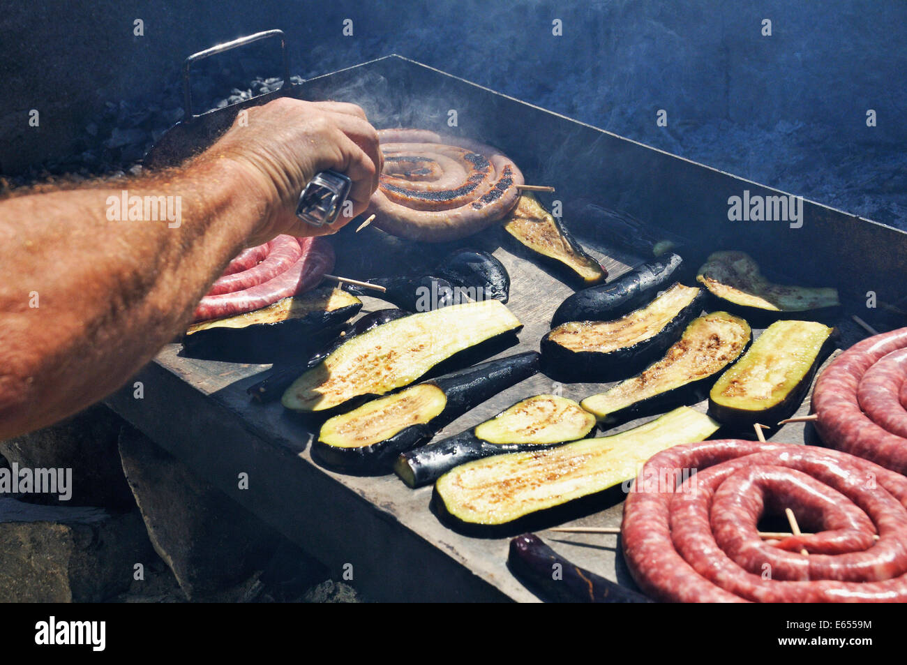 Sausages and eggplants / avocado cooking on a barbecue BBQ Stock Photo