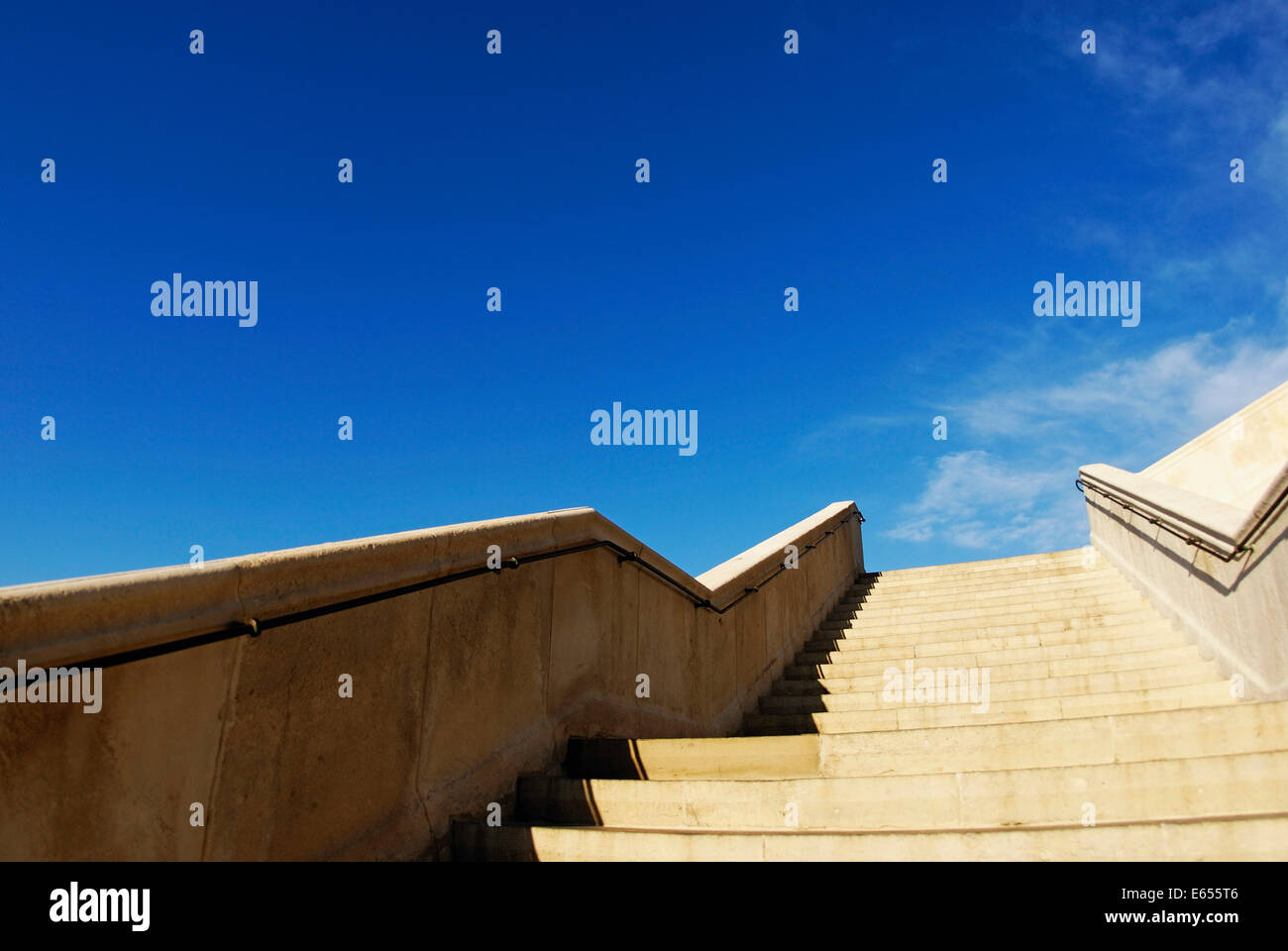 Looking up a stone stairs, steps, staircase going up to blue sky outdoors Stock Photo