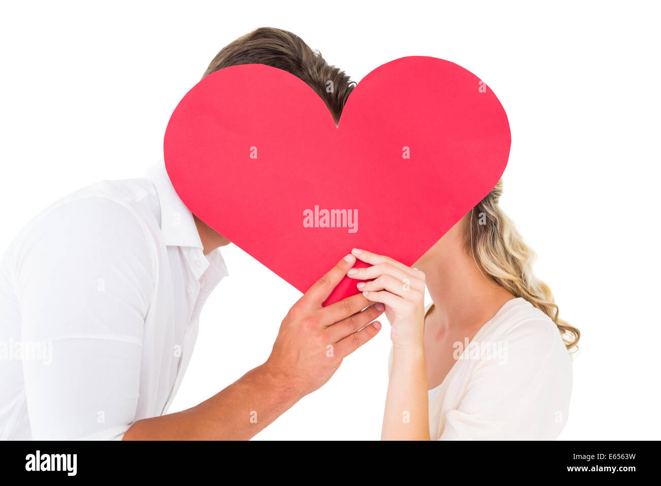 Attractive young couple kissing behind large heart Stock Photo - Alamy