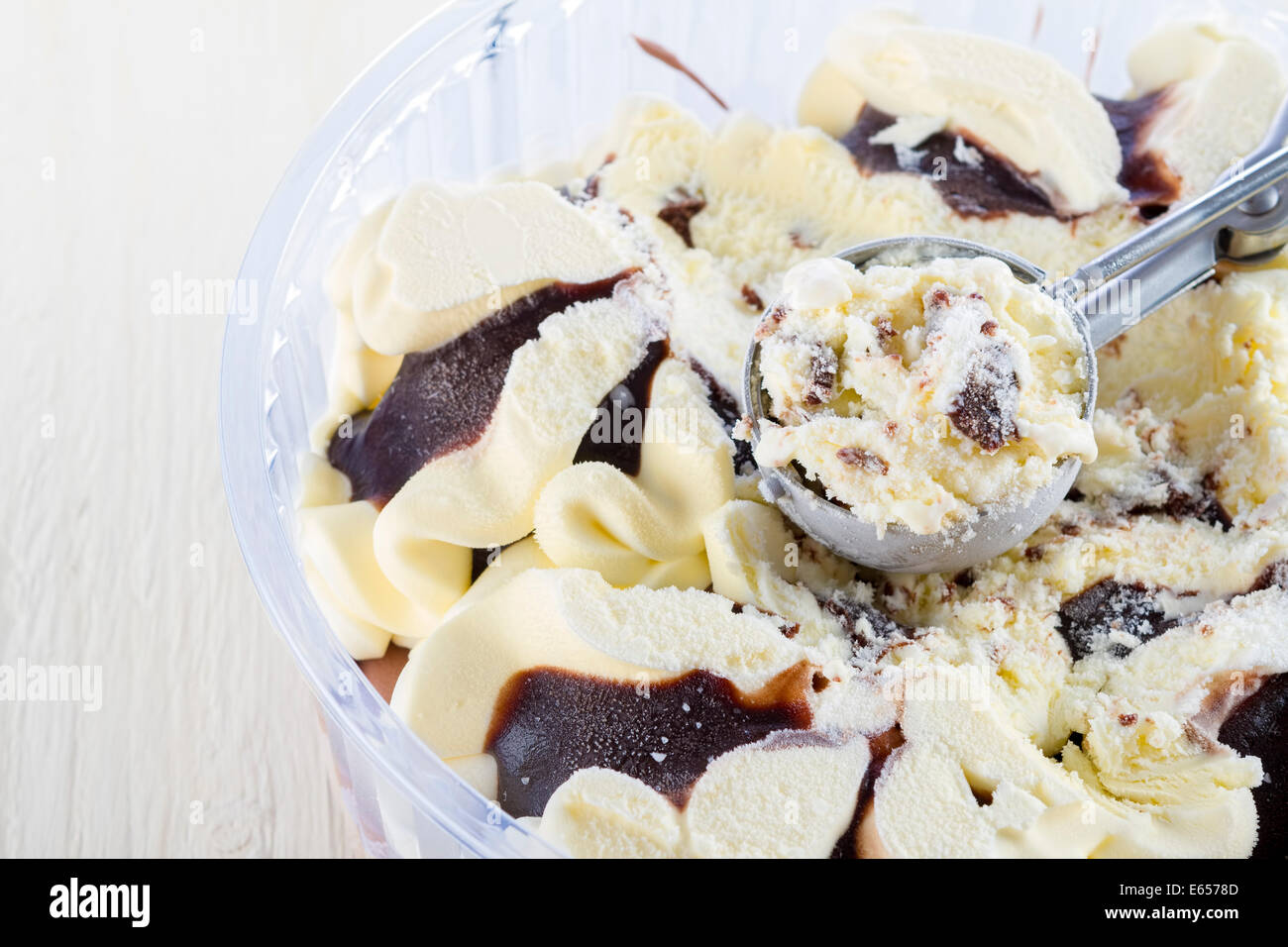 vanilla with chocolate ice cream scoop scooped out of a container on white wooden background Stock Photo